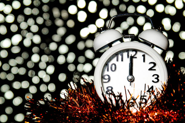 istock New Year at Midnight. Clock at twelve o'clock with holiday lights 1353657474