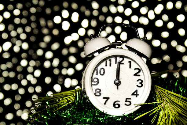 istock New Year at Midnight. Clock at twelve o'clock with holiday lights 1353657635