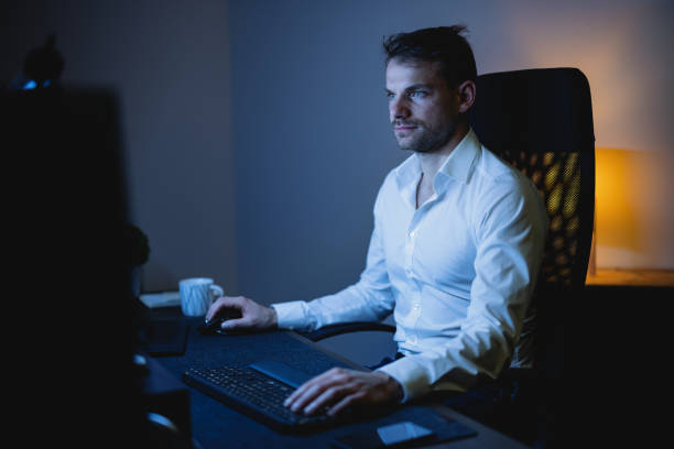 istock Businessman using his desktop PC in the office late at night 1353658314