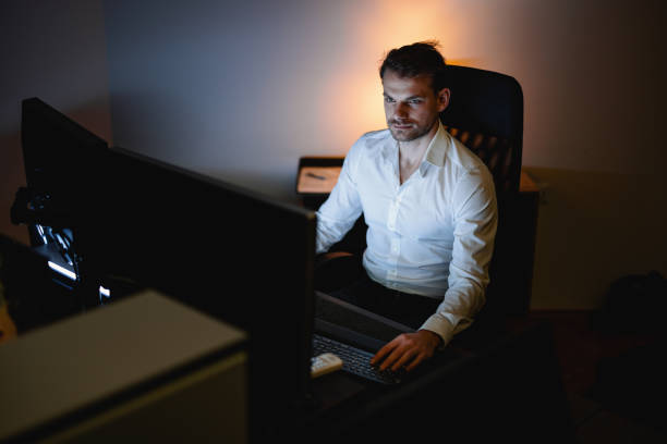 istock Businessman using his desktop PC in the office late at night 1353658385