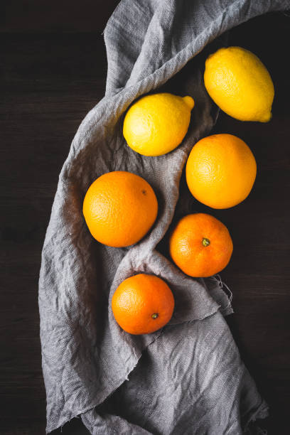 citric fruits Top view of a variety of citric fruits: oranges, lemons and tangerines on a grey linen rag, on a dark wooden table valencia orange photos stock pictures, royalty-free photos & images