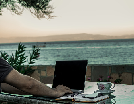 Professional freelancer business man working from laptop with high technology. Writer works from notebook in his summer house in vacation in pandemic