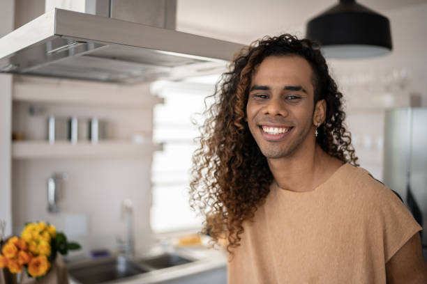 Portrait of a happy young man at home Portrait of a happy young man at home gay long hair stock pictures, royalty-free photos & images