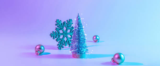 istock Neon Christmas winter background. Minimal abstract tree, xmas gift box. Holiday decoration bauble ball on neon gradient backdrop. Happy new year copy space. 1353662191