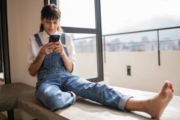 istock Young woman using the mobile phone at home 1353662455