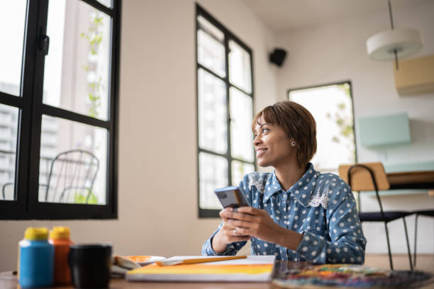 istock Young woman panting, using a mobile phone and contemplating at home 1353662702