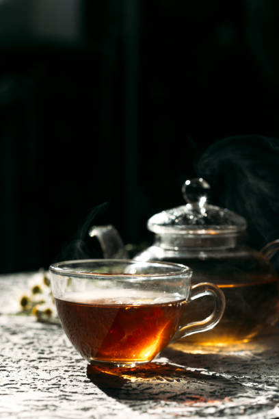 istock Warm cup of tea with glass teapot on dark background 1353662903
