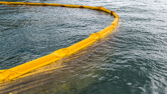 Floating boom barrier containing a film of oil and dirt. A containment boom is a temporary floating barrier used to contain an oil spill.