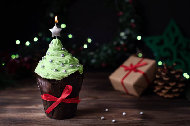 istock Christmas tree-shaped cupcake with a star candle and gifts. 1353664286