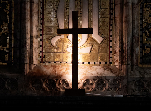 A simple back lit cross standing on an altar in an English church.