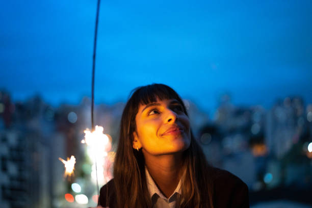 Contemplative young woman looking at the sky and holding a sparklers on New Year at home Contemplative young woman looking at the sky and holding a sparklers on New Year at home women satisfaction decisions cheerful stock pictures, royalty-free photos & images