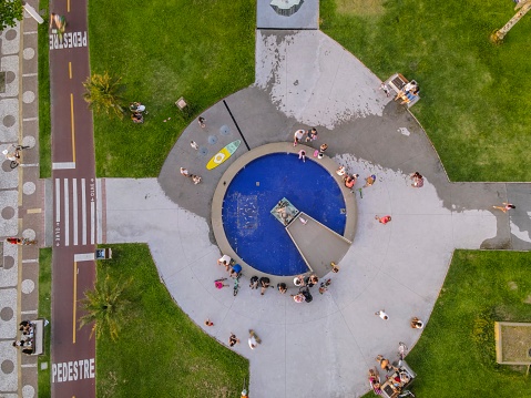 Santos, São Paulo, Brazil - November 15, 2021: Families enjoying the late afternoon at Alderman Luiz La Scala Square. Fisherman's monument, fountain, bike path and waterfront gardens seen from above.