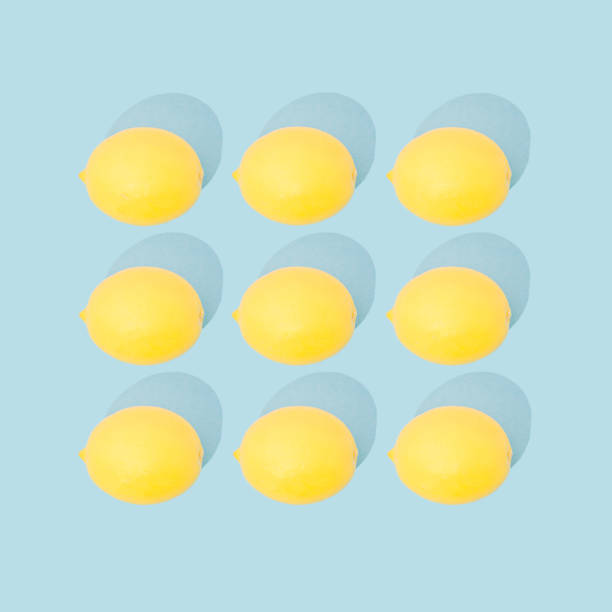 Trendy sunlight Summer pattern made with yellow lemon on bright light blue background. Minimal summer concept.