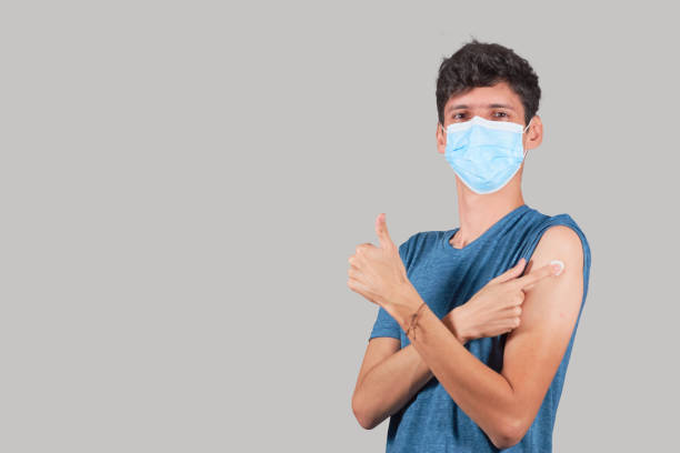 istock Young Latino man approves the vaccine, just vaccinated. Isolated on plain background. 1353669938