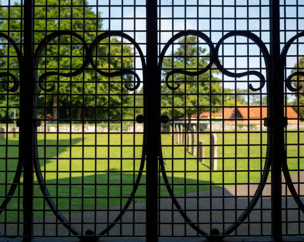 A view through church gates into the churchyard at the parish church of St James the Great in the pretty village of Castle Acre near Swaffham in Norfolk, Eastern England.