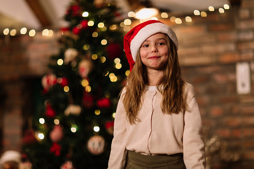 Portrait shot of a young girl standing in front of a Christmas tree