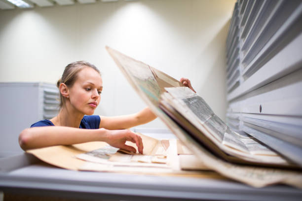 Pretty, young woman studying an old book in archives