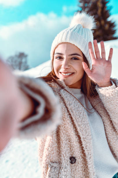 istock Smiling Female Showing Greeting While Taking Selfie On Snowy Mountain 1353675819