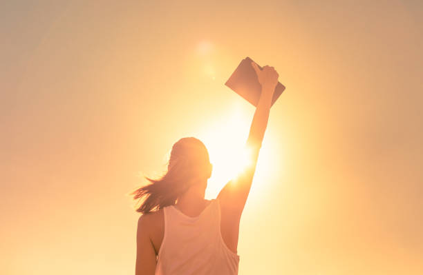 Winner. Woman holding bible in the sky. stock photo
