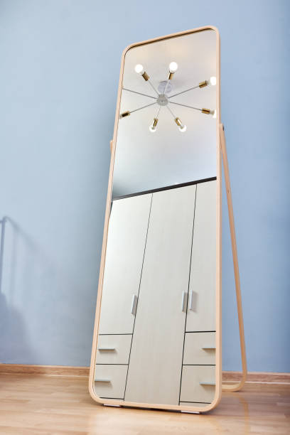 istock Full-length standing floor mirror in room with blue wall. 1353676233