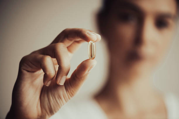 женщина показывает витаминную капсулу - vitamin e capsule medicine pill стоковые фото и изображения