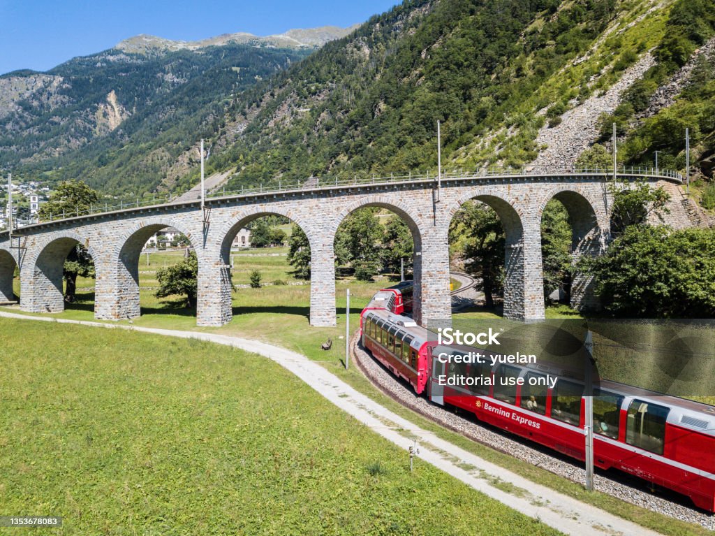 Bernina Express is going through the famous Brusio circular viaduct Brusio, Switzerland: 26 August 2018 - Bernina Express is going through the famous circular viaduct in Swiss Alps mountain, Canton Grisons, This spiral viadukt is a unesco heritage. opened in 1908. Above Stock Photo