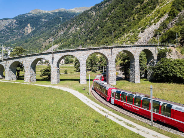 bernina express is going through the famous brusio circular viaduct - bernina express imagens e fotografias de stock