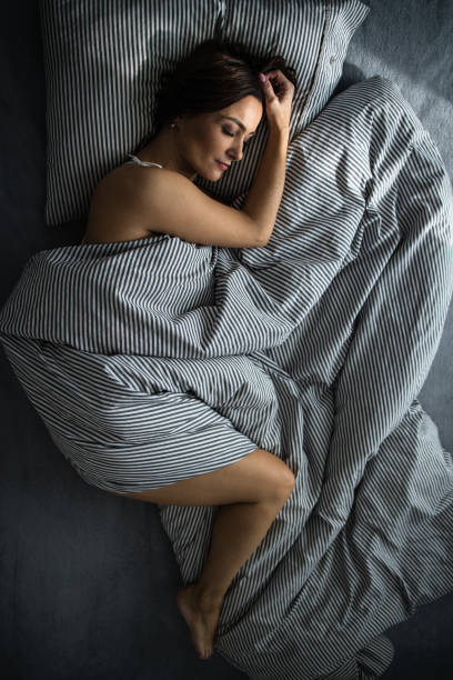 Beautiful woman with curly hair sleeping on comfortable bed at the bedroom. African female sleeping on comfortable bed. Sleepy girl sleeps soundly and does not want to wake up in the morning.