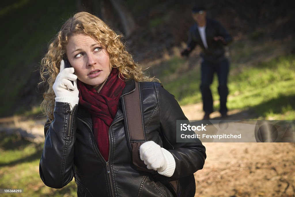 Linda jovem adolescente caminhando com homem à espreita lá atrás dela - Foto de stock de Mulheres royalty-free