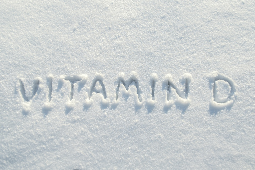 Inscription vitamin D on clean snow, in the bright rays of the winter sun. Health concept. Copy space. Top view.