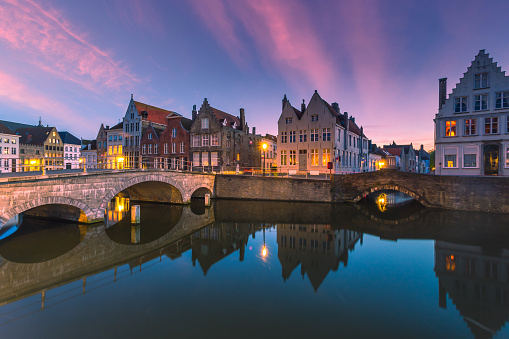 Church of Our Lady tower, Gruuthuse bridge across Dijver water canal, tourists boat near wharf and medieval buildings in Brugge old town quarter, Bruges city historic centre, Flemish Region, Belgium