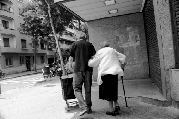 Asian elderly man pushing his wife in wheelchair at park. Senior couple enjoying leisurely stroll, surrounded by lush greenery. relaxation in public park of senior couple. copy space