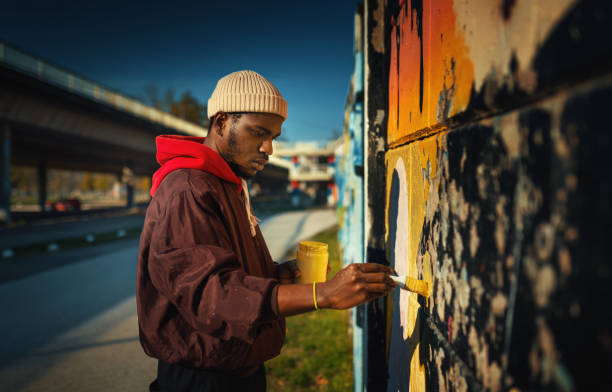 Street artist drawing graffiti on the wall. Closeup side view of a young African American man creating street art drawing on the wall. streetart stock pictures, royalty-free photos & images