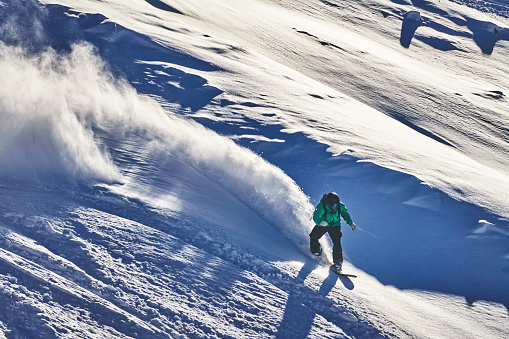 He sprays snow as he turns at speed, in the snowy Swiss Alps