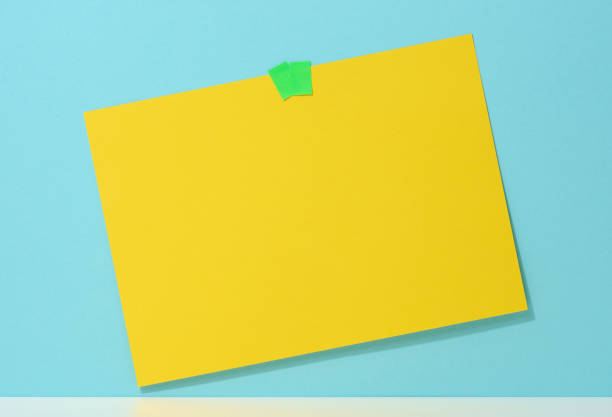 istock blank rectangular yellow sheet of paper glued on a blue background. Place for an inscription, announcement 1353687520