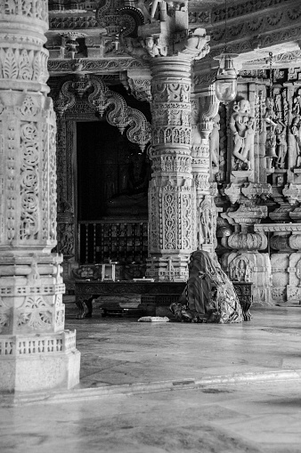 Ranakpur, Rajasthan, India - oct 18, 2011 : a woman prays among the marble columns of the Jain temple of Ranakpur, 90 km north of Udaipur, in Rajasthan