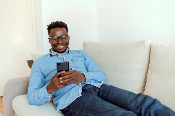 istock Cheerful black man using mobile wearing eyeglasses, texting and browsing internet. 1353691508