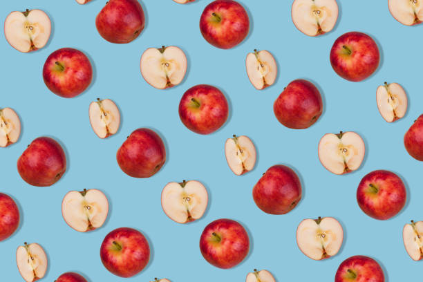 istock Trendy pattern of fresh whole apple and halves on  pastel blue background. 1353691742