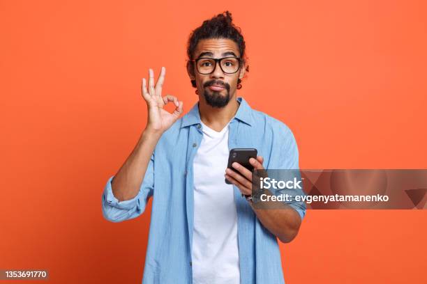 Isolated Studio Shot Of Young African American Man Showing Ok Sign With Mobile Phone In Hand Stock Photo - Download Image Now