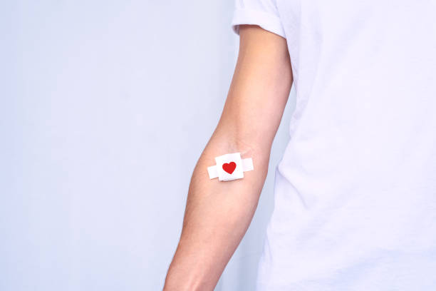 don de sang. donneur de sang avec bandage après avoir donné du sang sur fond blanc. espace de copie - don du sang photos et images de collection