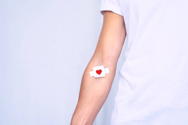 Blood donation. Blood donor with bandage after giving blood on a white background. Copy space Blood donation. Blood donor with bandage after giving blood on a white background. Copy space. High quality photo blood donation stock pictures, royalty-free photos & images