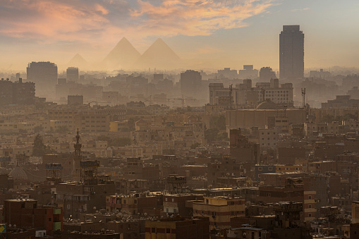Aerial view of Cairo city in Egypt and pyramid silhouettes in back.