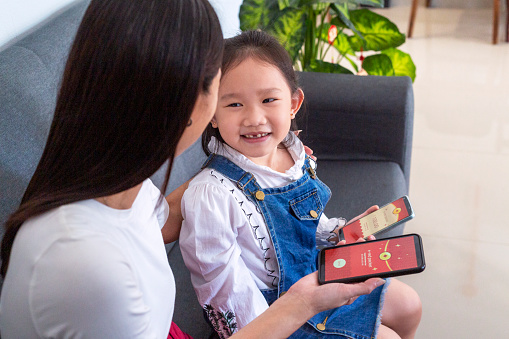 chinese new year red envelope transfered digitally - young mother giving recpacket during festival using mobile app