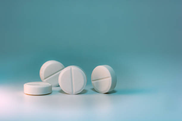 istock Several white pills on a blue-green background with turquoise. 1353694214