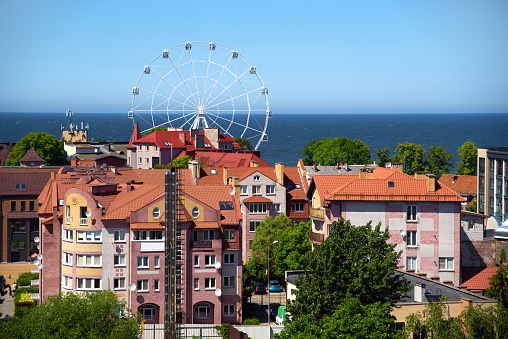 View of resort town Zelenogradsk (formerly Cranz) at Baltic Sea in the Kaliningrad (formerly Konigsberg) region, Russia. Modern residential multi-storey buildings, blue sky and sea, ferris wheel