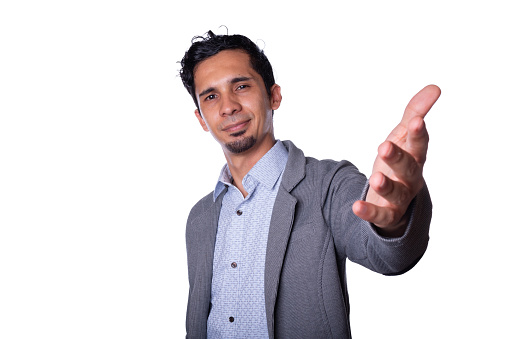 Modern businessman smiles and stretches his hand to the camera wishing to greet, Young latin man wearing modern elegant clothes, isolated on white background.
