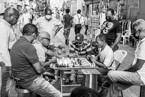 Santo Domingo, Dominican Republic. Men playing and watching the game in a crowded downtown market in the Dominican Republic.