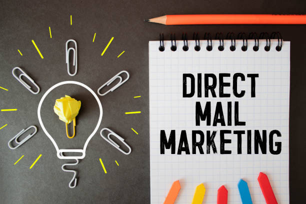 istock pen and notebook written with DIRECT MAIL MARKETING on wooden background. 1353698021