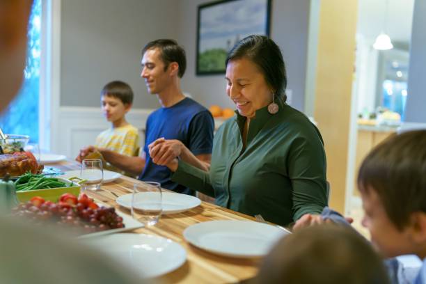 istock Family saying grace at holiday dinner table 1353700270