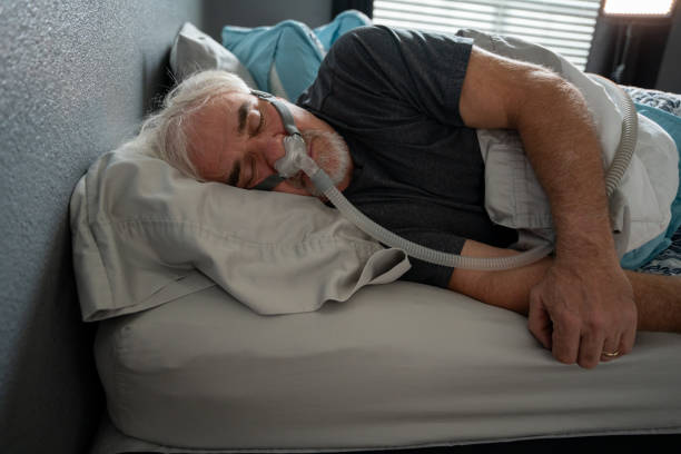 istock Mature Man Sleeping with a CPAP (Continuous positive airway pressure) Machine after being diagnosed with Sleep Apnea 1353714097